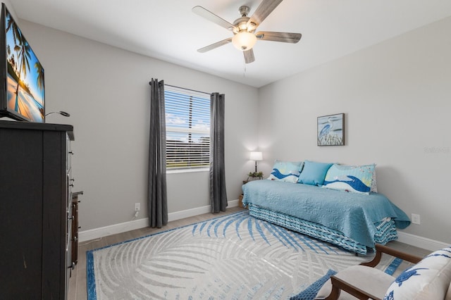 bedroom with a ceiling fan, baseboards, and wood finished floors