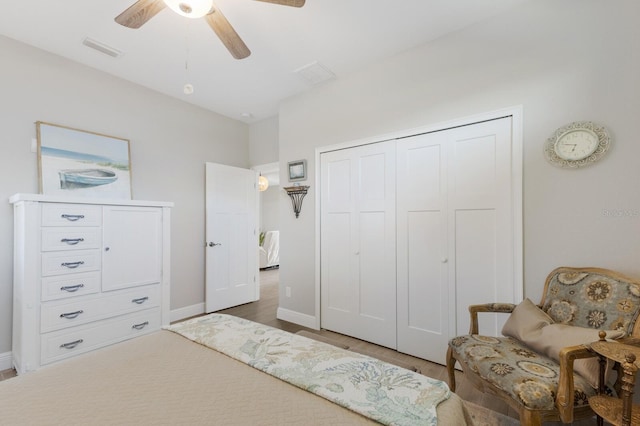 bedroom with baseboards, visible vents, a ceiling fan, wood finished floors, and a closet