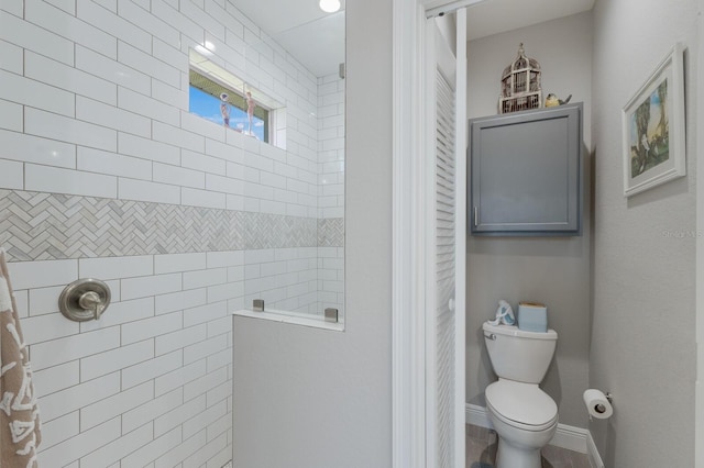 bathroom with a walk in shower, toilet, and baseboards