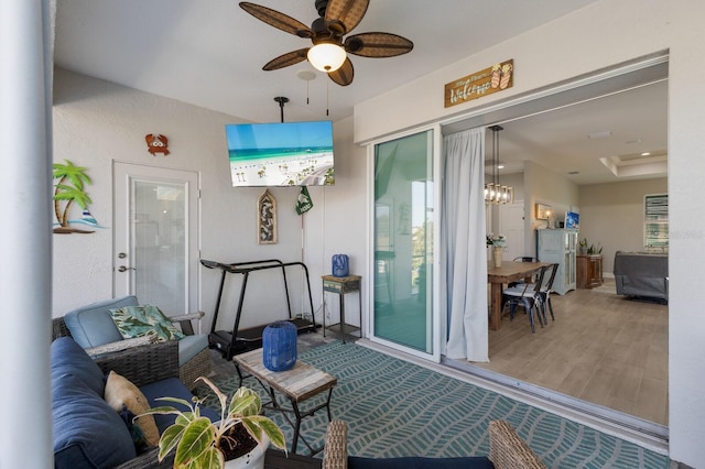 sunroom with a raised ceiling and ceiling fan