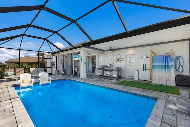 outdoor pool with ceiling fan, a patio area, and a lanai