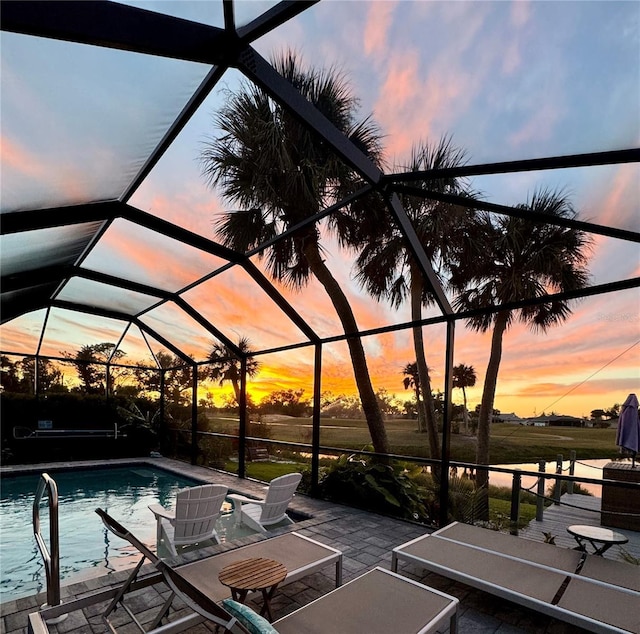 pool at dusk with an outdoor pool, a lanai, and a patio