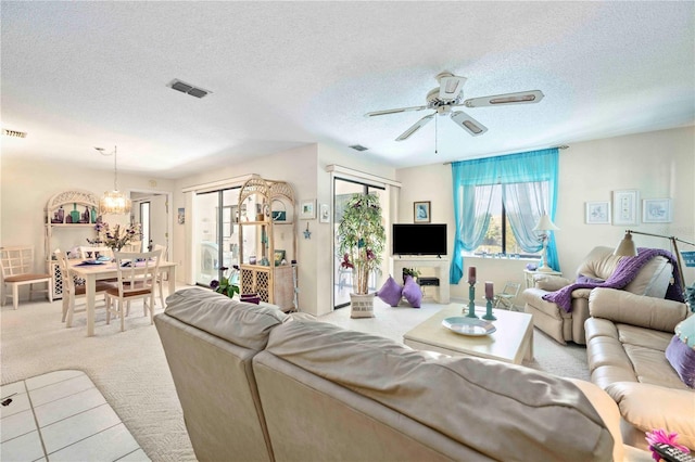 living area with visible vents, ceiling fan with notable chandelier, a textured ceiling, and carpet floors