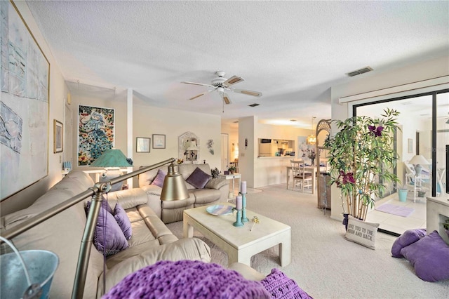 living room with visible vents, carpet flooring, a textured ceiling, and ceiling fan