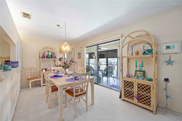 dining space featuring visible vents, baseboards, a chandelier, light colored carpet, and a textured ceiling