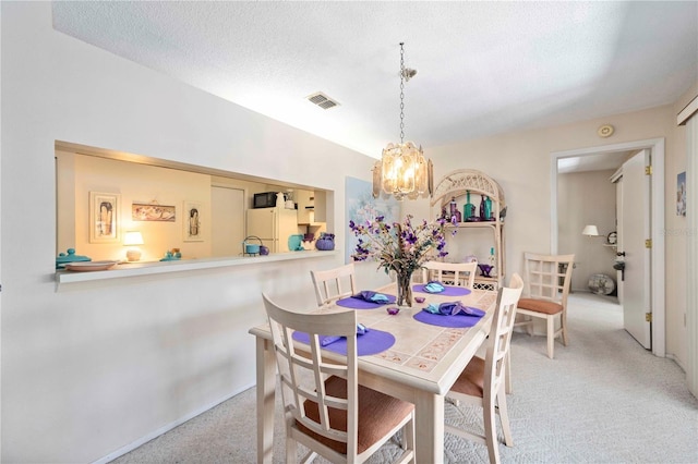 carpeted dining area featuring visible vents, a textured ceiling, and a notable chandelier