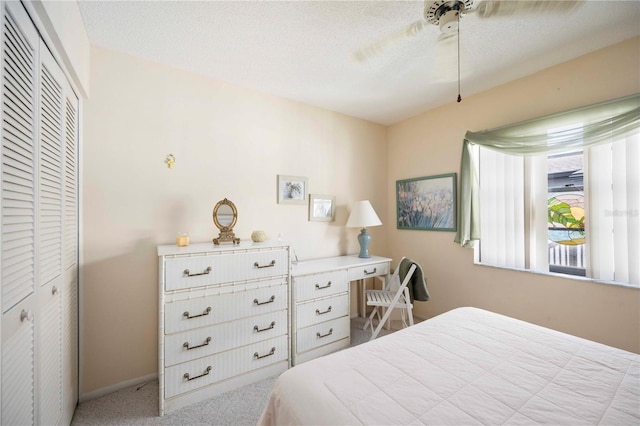 carpeted bedroom with ceiling fan, a closet, and a textured ceiling