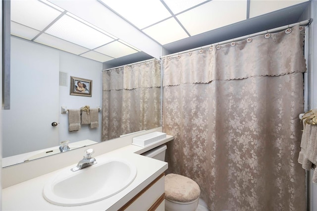 full bath featuring a drop ceiling, toilet, vanity, and a shower with curtain