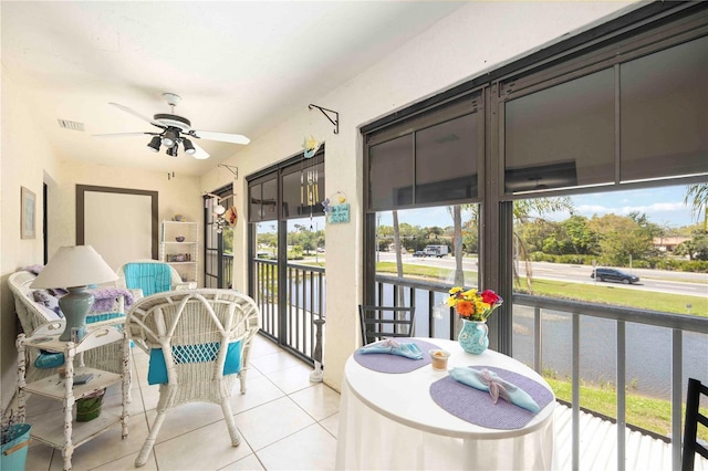 sunroom with visible vents, a healthy amount of sunlight, ceiling fan, and a water view