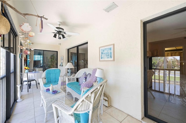 sunroom / solarium with plenty of natural light, a ceiling fan, and visible vents