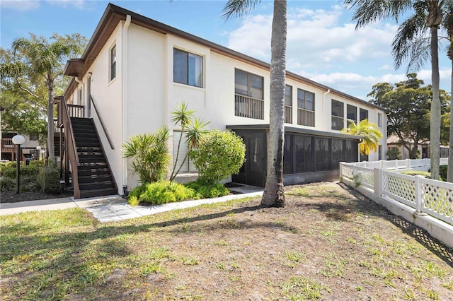 multi unit property featuring stairway, stucco siding, and fence