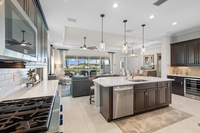 kitchen featuring beverage cooler, visible vents, a tray ceiling, stainless steel appliances, and a sink