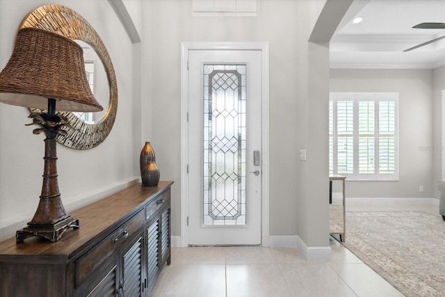 entryway with light tile patterned floors, baseboards, and crown molding