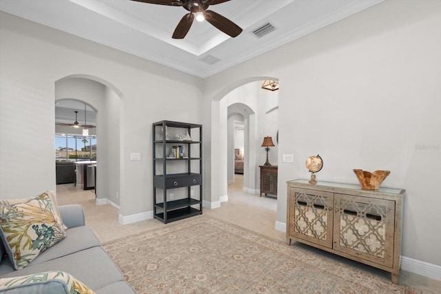 living area featuring arched walkways, a raised ceiling, visible vents, a ceiling fan, and baseboards