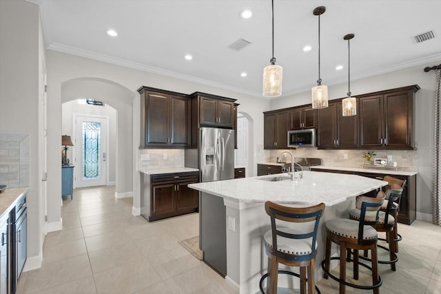 kitchen featuring visible vents, arched walkways, stainless steel appliances, and a sink