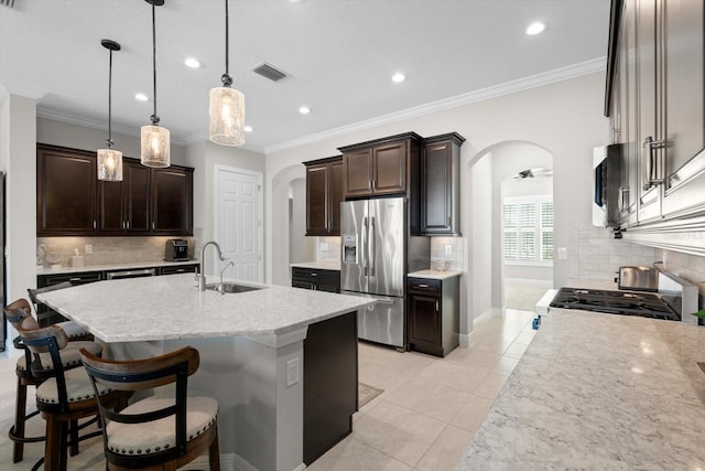 kitchen with visible vents, arched walkways, stainless steel appliances, dark brown cabinets, and a sink