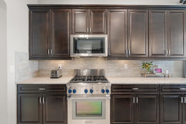 kitchen with light stone countertops, appliances with stainless steel finishes, decorative backsplash, and dark brown cabinets