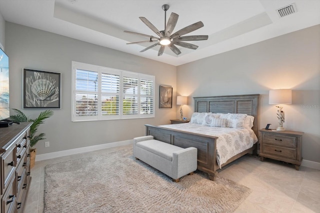 bedroom featuring ceiling fan, a tray ceiling, visible vents, and baseboards