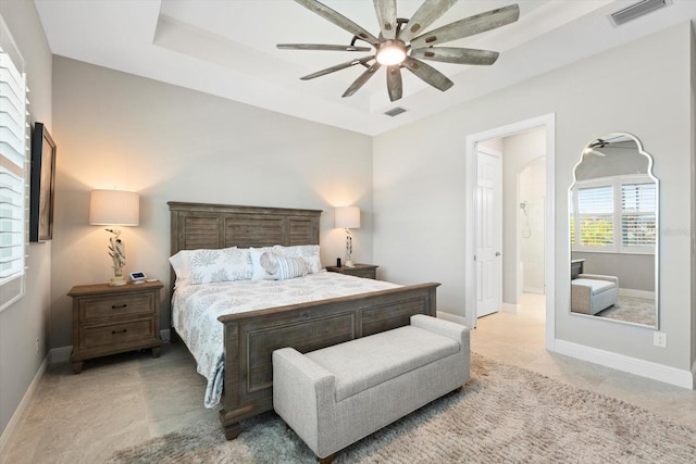 bedroom with a tray ceiling, visible vents, and baseboards