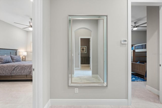 bedroom featuring baseboards, arched walkways, and ceiling fan