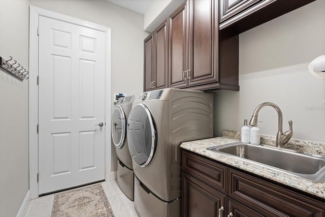 clothes washing area featuring cabinet space, light tile patterned floors, washer and clothes dryer, and a sink