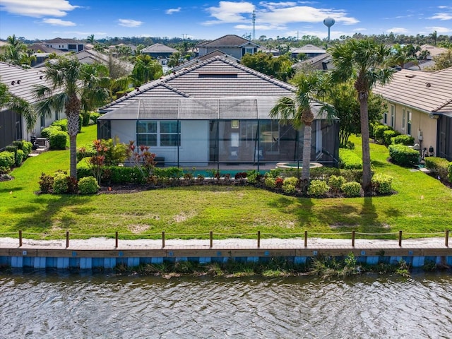 rear view of house featuring a water view, a tiled roof, and a yard