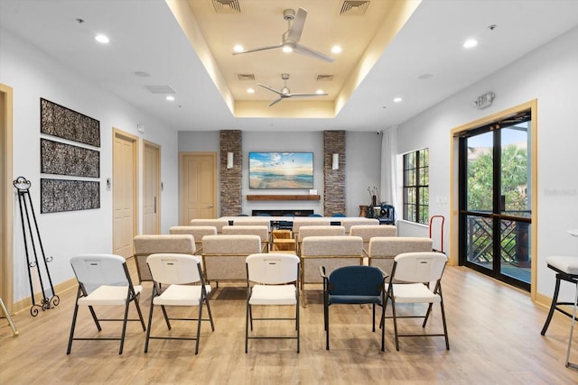 cinema with a tray ceiling, visible vents, and light wood-style floors