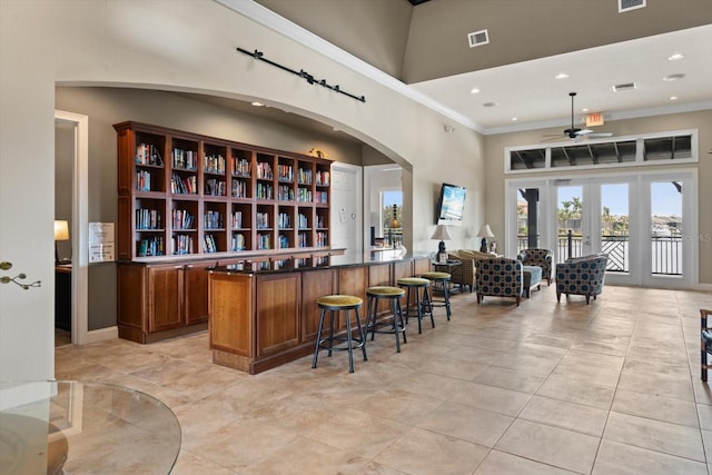 bar featuring french doors, visible vents, crown molding, and a high ceiling