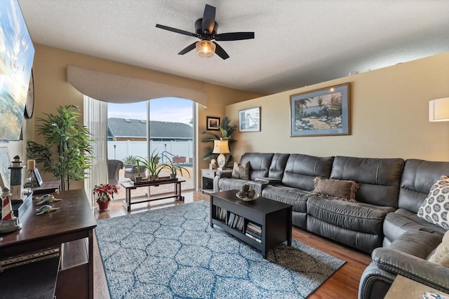 living room featuring ceiling fan, a textured ceiling, and wood finished floors