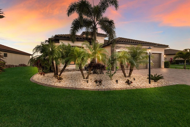 exterior space with a garage, a front lawn, decorative driveway, and stucco siding