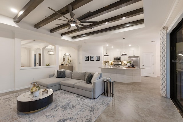 living room with arched walkways, ceiling fan, recessed lighting, baseboards, and beam ceiling