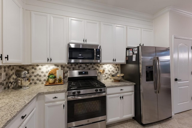 kitchen featuring light stone counters, light tile patterned flooring, white cabinetry, appliances with stainless steel finishes, and tasteful backsplash