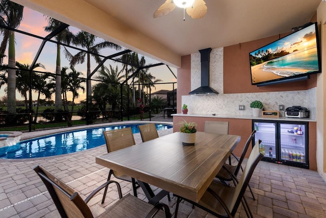 view of swimming pool with glass enclosure, a patio area, a pool with connected hot tub, and ceiling fan