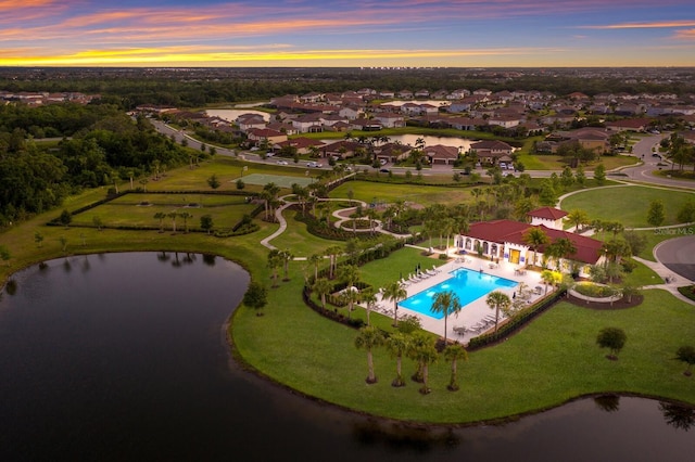 aerial view at dusk featuring a water view and a residential view