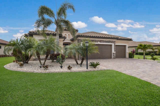 mediterranean / spanish house with an attached garage, a tiled roof, decorative driveway, and a front yard