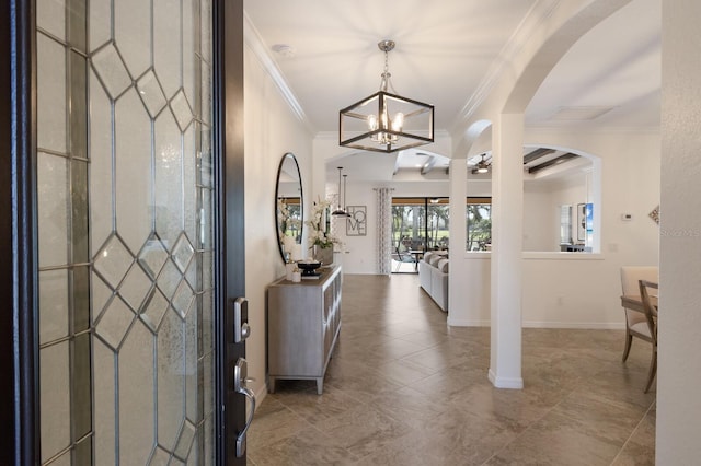 foyer featuring arched walkways, crown molding, and baseboards