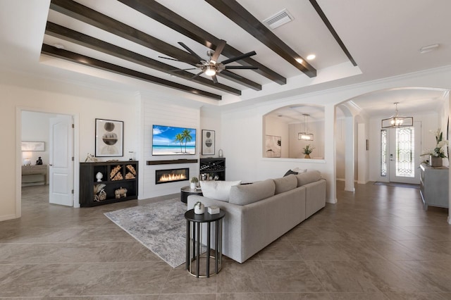 living room with arched walkways, visible vents, a large fireplace, beamed ceiling, and ceiling fan with notable chandelier