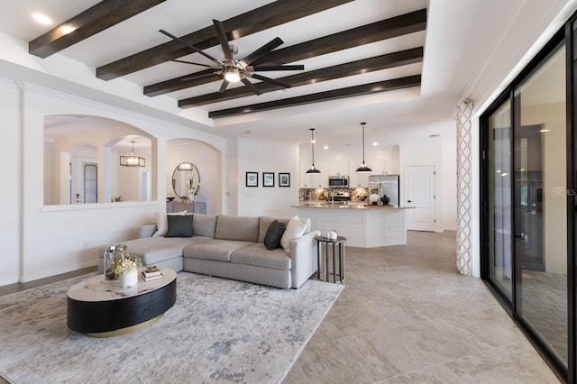 living room featuring arched walkways, beamed ceiling, baseboards, and recessed lighting