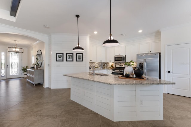 kitchen featuring arched walkways, appliances with stainless steel finishes, ornamental molding, white cabinetry, and a sink