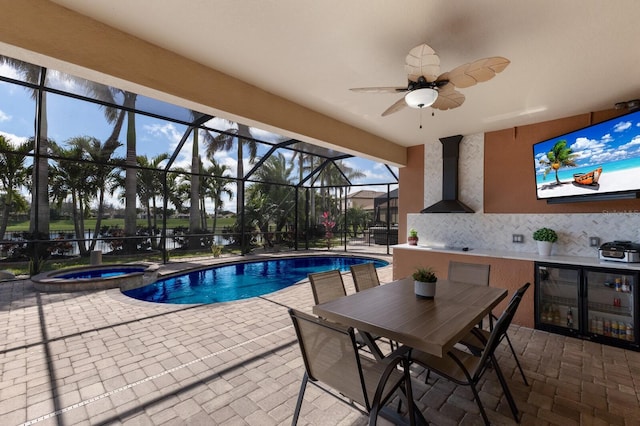 view of pool with a patio, a lanai, a pool with connected hot tub, exterior kitchen, and outdoor dining space