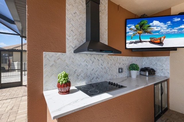 kitchen featuring tasteful backsplash, light stone countertops, wall chimney exhaust hood, and black electric cooktop