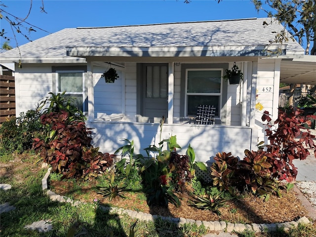 view of front of home featuring a porch, roof with shingles, and a carport