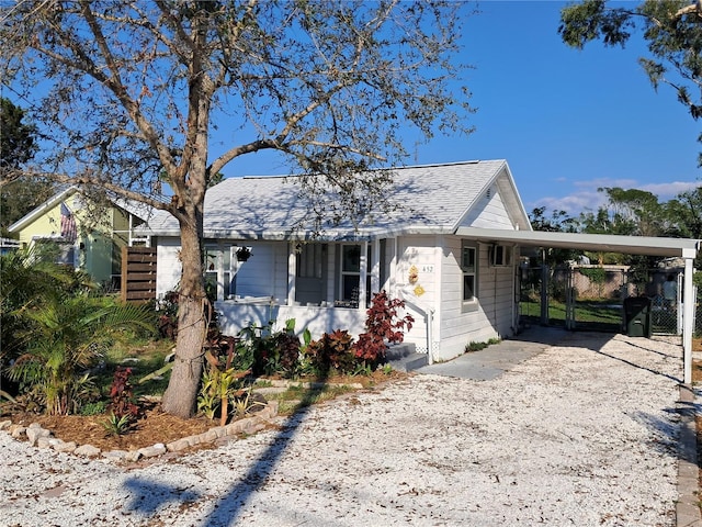 ranch-style home featuring gravel driveway, a shingled roof, and an attached carport