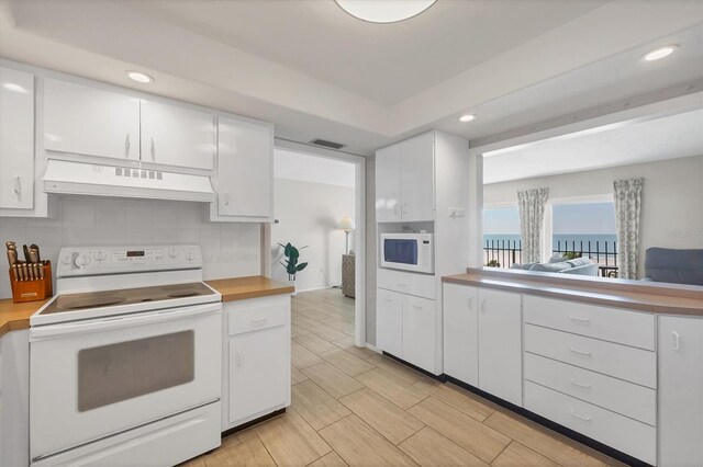 kitchen with white cabinetry, white appliances, tasteful backsplash, and under cabinet range hood