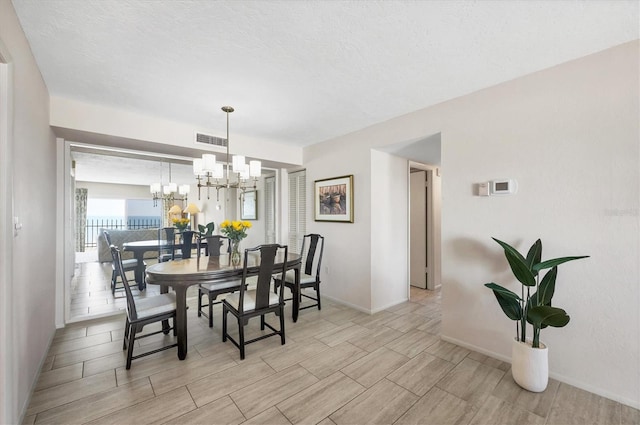 dining area featuring a notable chandelier, visible vents, baseboards, and wood tiled floor