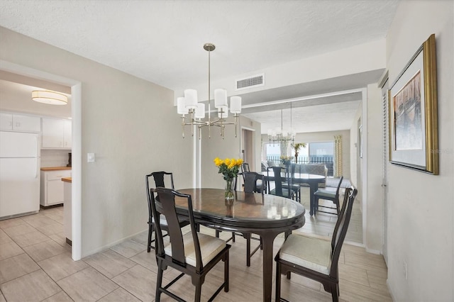 dining room with a chandelier, visible vents, and baseboards