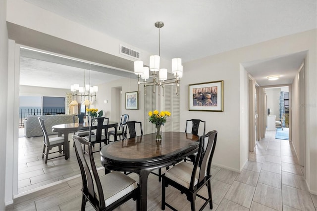 dining space with an inviting chandelier, baseboards, and visible vents