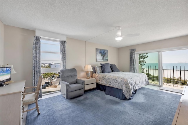 carpeted bedroom with access to exterior, a ceiling fan, a water view, and a textured ceiling