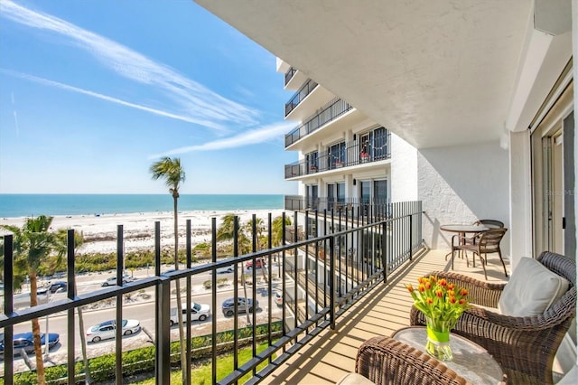 balcony featuring a view of the beach and a water view
