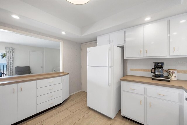 kitchen with light wood-style flooring, white cabinets, light countertops, and freestanding refrigerator